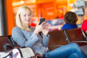 Młoda kobieta korzystająca z telefonu komórkowego siedząc na laptopie