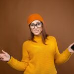 Świetna aplikacja uśmiechnięta brunetka ze smartfonem w rękach pozująca na czerwonym tle i