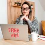 Młoda kobieta używająca laptopa siedząc na stole