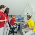 Zespół medyczny dentysta w gabinecie stomatologicznym omówić i zbadać obraz rentgenowski patrząc na komputer
