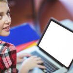 Blondynka uczeń używa laptop podczas klasy