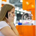 Młoda kaukaska dziewczyna rozmawia przez smartfon za pomocą ikony 5g