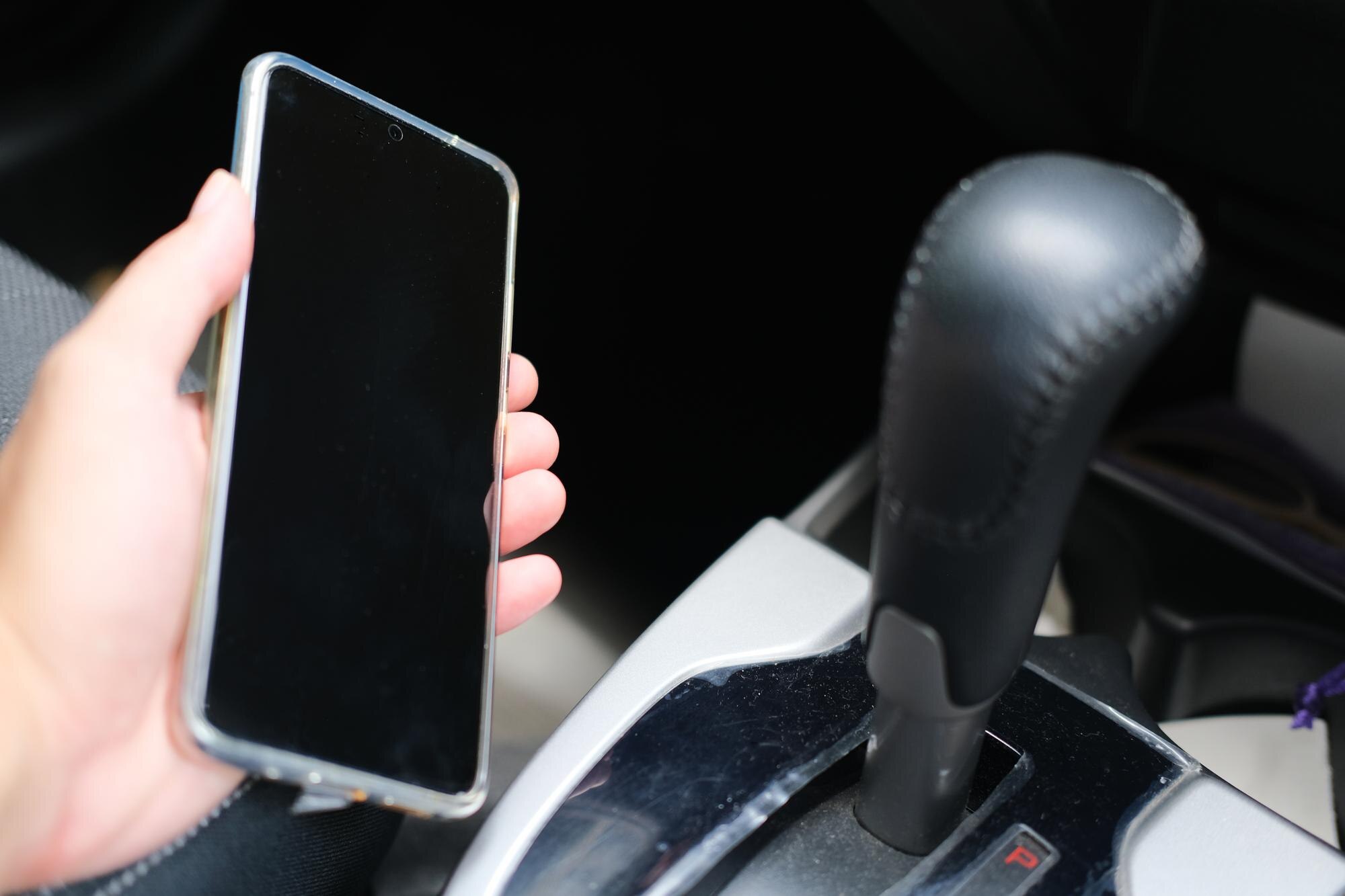 Ręka osoby trzymającej telefon komórkowy w samochodzie