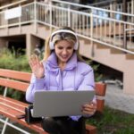 Studentka podczas przerwy rozmawia z przyjacielem przez rozmowę wideo w słuchawkach na ulicy