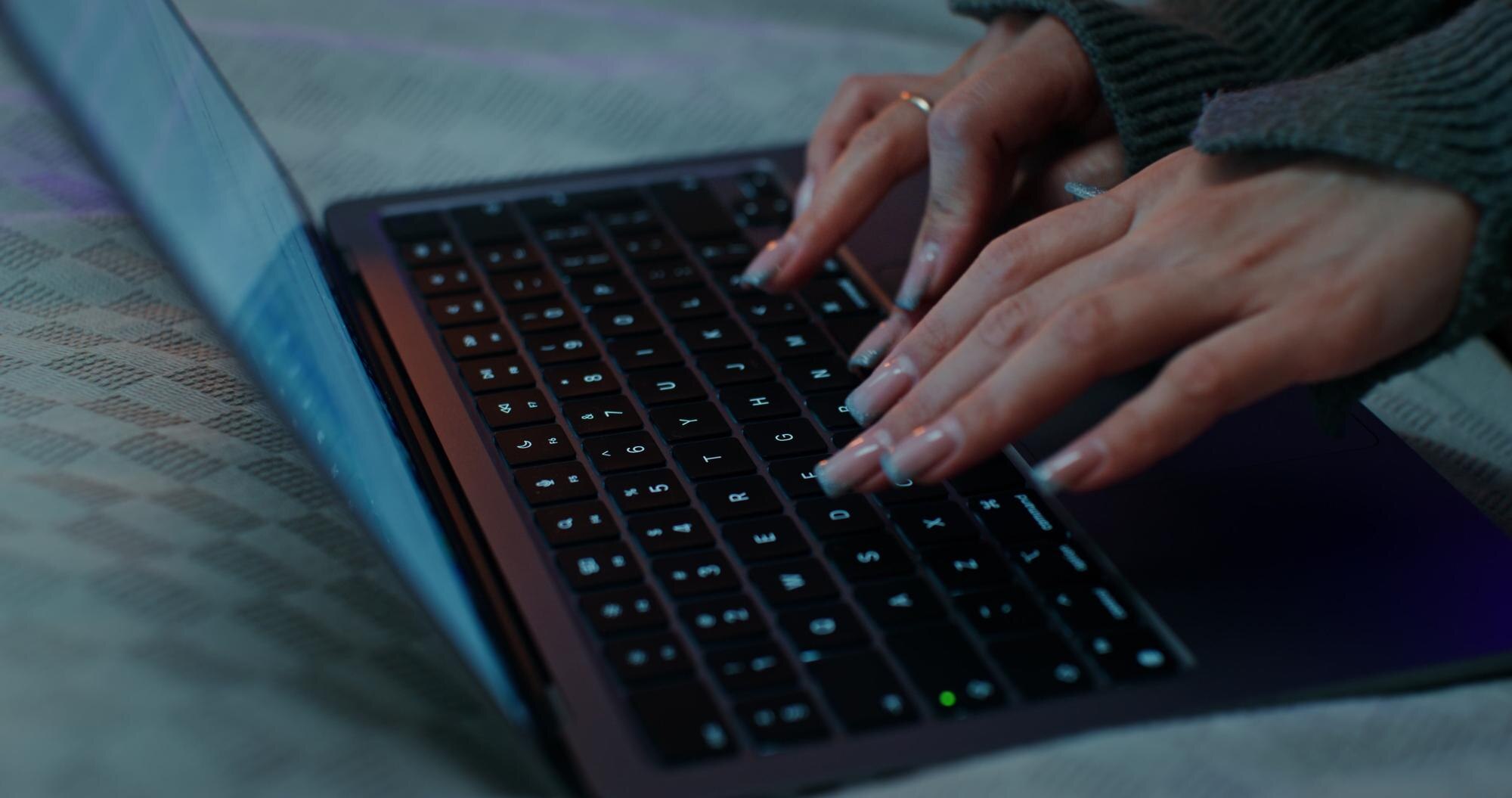 Kobieta używa laptopa siedząc na łóżku