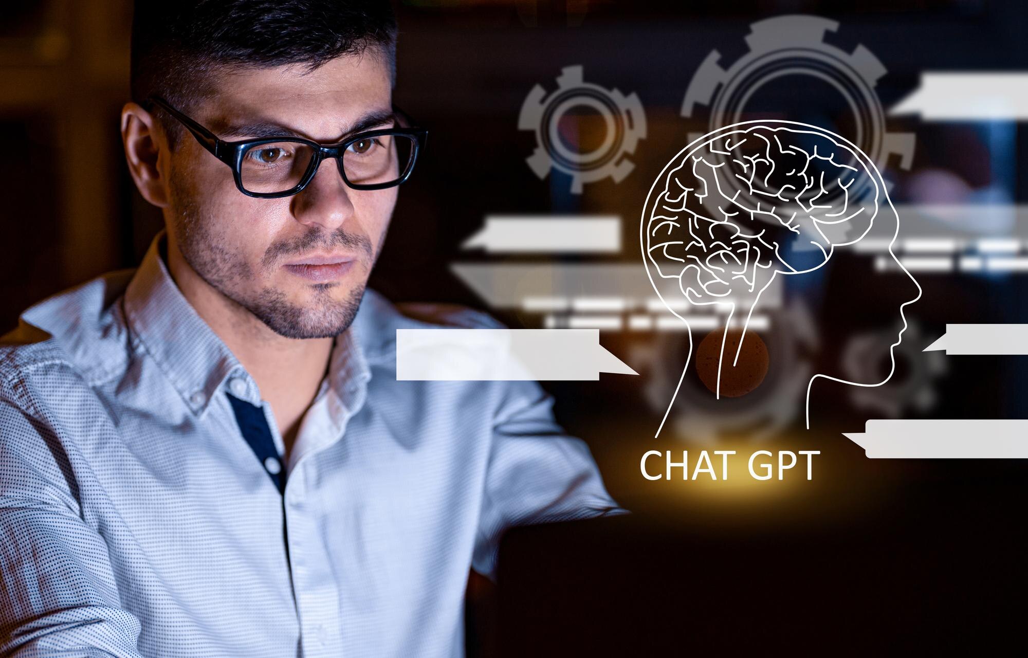Młody mężczyzna w okularach pracujący na laptopie za pomocą czatu gpt