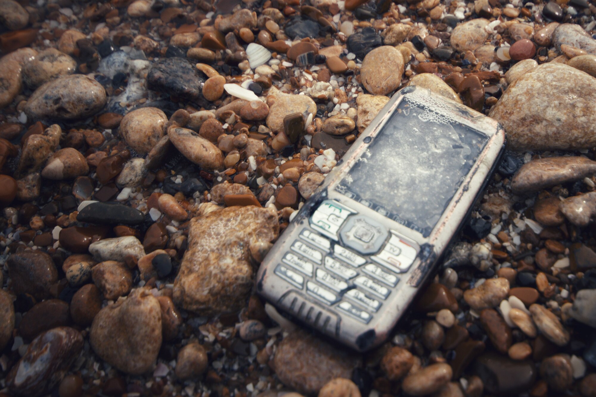 połamany i utopiony telefon na kamieniach w morzu