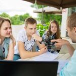 Grupa młody studencki używa laptop plenerowy